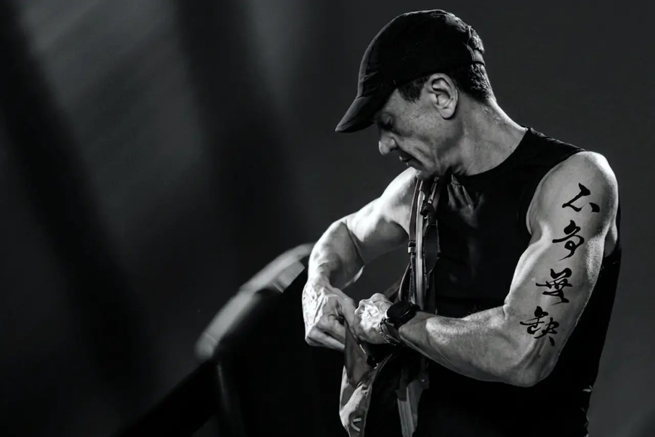 Traditional brush-script Chinese characters for "Bu Zheng Wu Que" tattooed on a man's upper arm