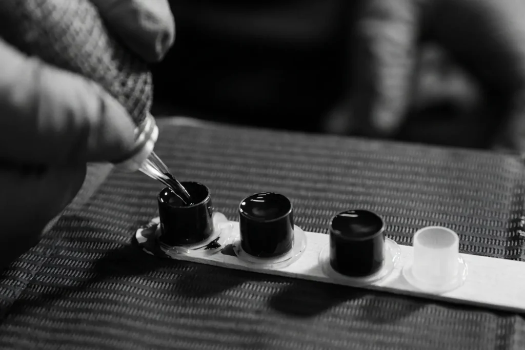 Macro shot of the tattoo process showing ink preparation and a steady hand with a tattoo pen
