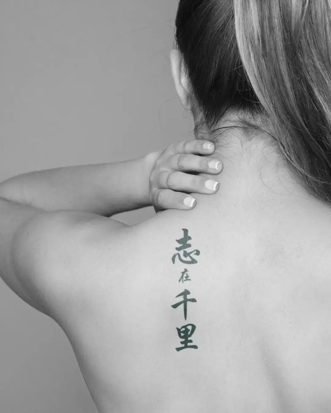 a Zhi Zai Qian Li tattoo inked on the upper back of a model