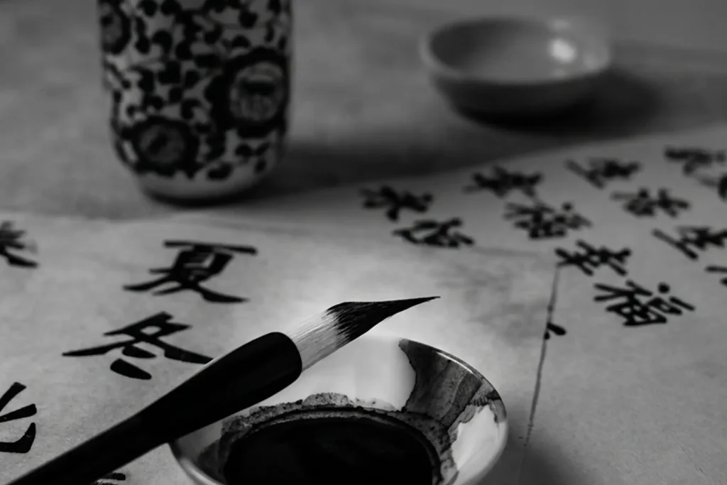 Close-up of a traditional Chinese calligraphy brush resting on an ink well with handwritten Hanzi characters.
